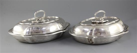 A pair of Edwardian silver shaped oval entreé dishes and covers with handles by Goldsmiths & Silversmiths Co Ltd, 98.5 oz.